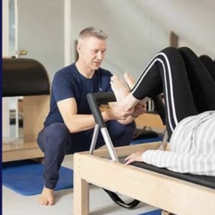 Adrian Bell working with a client on a Pilates reformer