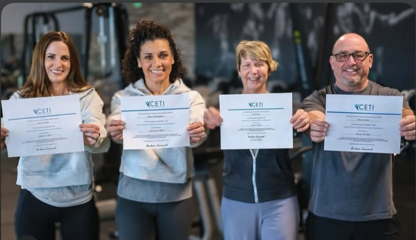 Four EVOKE Warriors staff members holding their OncoVie Cancer Exercise Specialist certificates in their gym